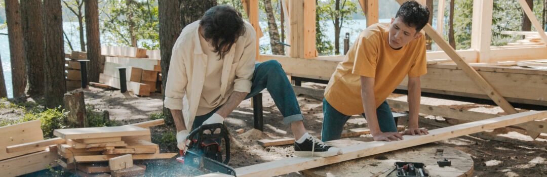 2 men cutting 2x4 building a house